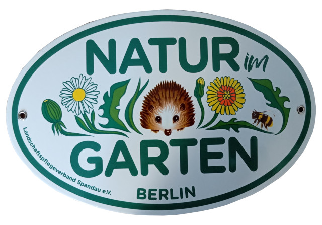 Ovales Email-Schild mit der Aufschrift Natur im Garten.  Im Zentrum des Bildes ist in naiver Malweise ein Igel abgebildet. Recht und links neben dem Igel sind Löwenzahnblüten und Blätter sowie ein Hummel gemalt. Am linken unteren Bildrand steht der Schriftzug: Landschaftspflegeverband Spandau e. V. ind unten im Zentrum des Randers in Großbuchstaben Berlin. 